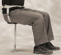 Adult male, pictured from torso downward, seated on the one-legged stool and strapped in as described.