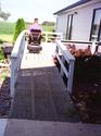 Side-by-side steel grid-work sheets affixed to the lower portion of a wooden ramp leading up to the deck entrance of a house.