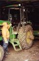 An adult male prepares to climb the three add-on steps that lead to the cab of his JD tractor.