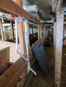 Inside of a barn with stalls on the left and a PVC waterline running above the stalls with a drain line hanging down