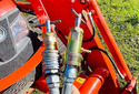 Front end of an orange tractor showing Hydraulic Pressure-Relief Tool attached to hydraulic lines